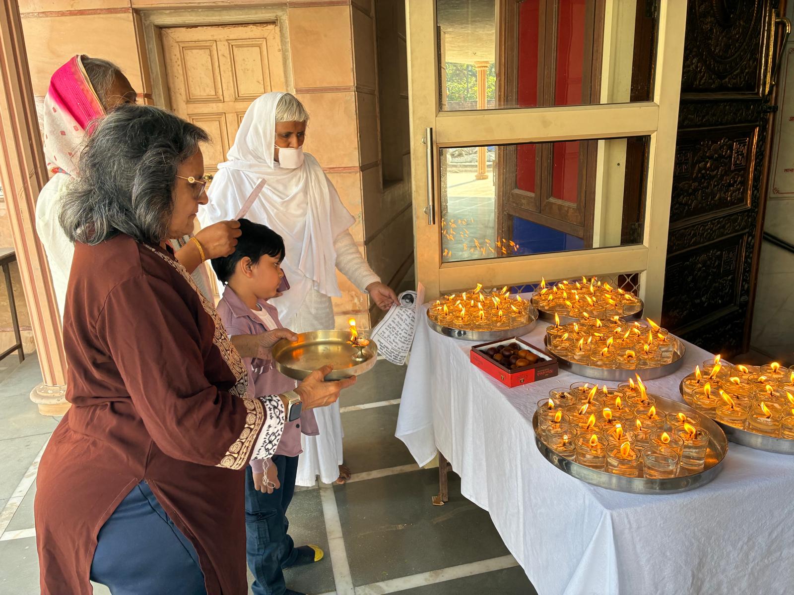 Family offering light beside rows of diyas